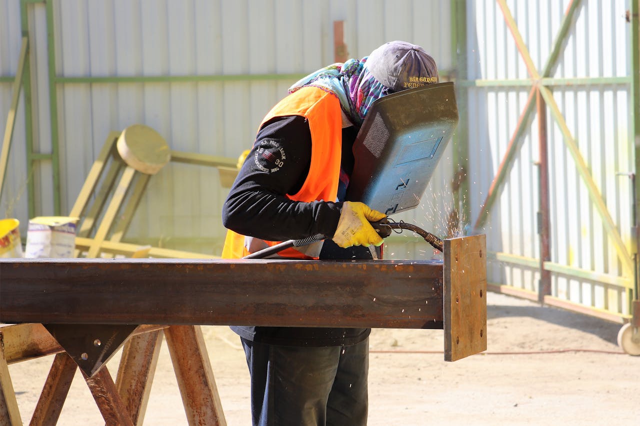 A construction worker skillfully welding a steel beam at an outdoor worksite.