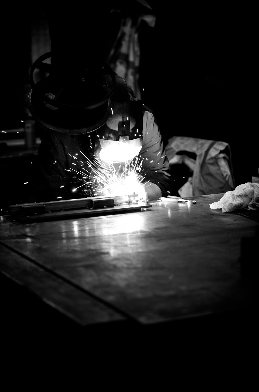 Welder at Work with Sparks Flying in Black and White A dramatic black and white photo capturing a welder mid-task, sparks flying as metal fuses under intense heat. This high-contrast industrial image showcases precision metalwork, safety gear, and the raw power of welding in a workshop environment. Perfect for themes around skilled labor, craftsmanship, tradespeople, and manufacturing.